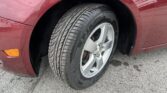 Close-up of a red car's front wheel and tire, showing the wheel well and alloy rim.