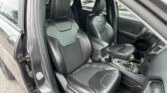 Open car door showing the black leather front seats and center console inside a vehicle. The driver and passenger seats are visible.