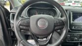 Close-up view of a Jeep steering wheel inside a car, with the instrument cluster and infotainment screen visible.