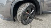 Close-up of a gray SUV front wheel and wheel well, showing the tire and fender.