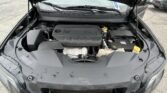 Open car hood exposing engine bay with a large black engine cover labeled 'MULTIAIR' and various hoses, reservoirs, and a yellow radiator cap visible on the right side cool system area.