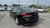Black Hyundai Sonata in the foreground of a crowded car dealership lot with white sedans and SUVs in the background under a cloudy sky.