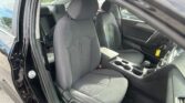 Front interior of a dark gray car with two front seats, center console, and steering wheel visible through the open driver's door.