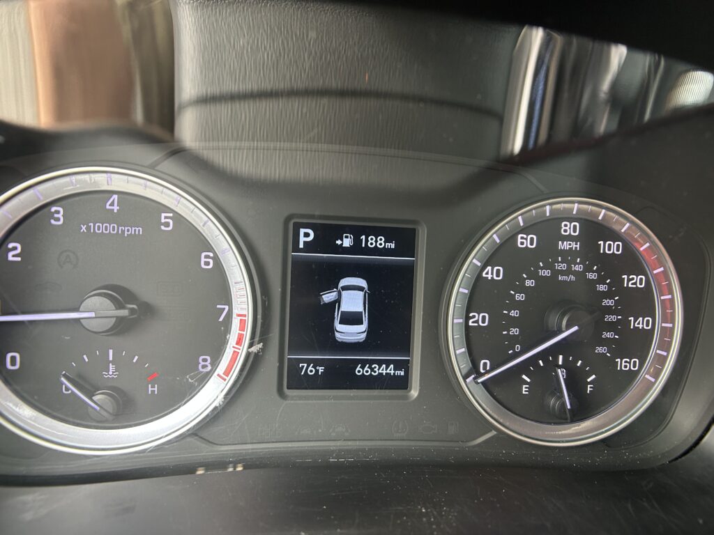 Car dashboard: left tachometer, right speedometer, center digital display showing parked gear, 188 mi range, and car icon; outside temp 76°F, odometer 66,344 mi.
