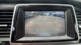 Rearview camera screen with parking guidelines and a street scene; text reads 'Check surroundings for your safety'.