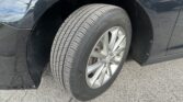 Close-up of a car’s front wheel and tire on a black vehicle, parked on pavement, with the wheel well visible.