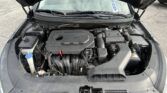 Open car hood exposing the engine bay, with the battery and fluid reservoirs visible under the windshield.