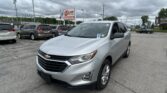 Silver Chevrolet SUV in foreground at a used car lot with multiple minivans parked behind; EZ Loan Auto Sales sign and cloudy sky overhead