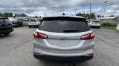 Rear of a silver Chevrolet Equinox parked in a lot, other cars around, cloudy sky above and power lines.