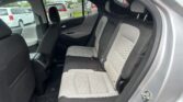 Back seat of a modern car with light gray quilted upholstery, two headrests, and three seat belts visible.