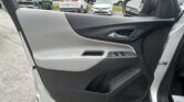 Driver-side car door panel with window controls; view of a busy parking lot outside through the door and mirror.