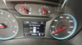 Car dashboard with tachometer on left and speedometer on right, red needles at mid-range, digital display below showing trip info and tire data