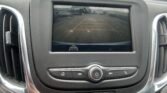 Back-up camera view on the dashboard screen showing yellow parking guide lines in a parking lot.