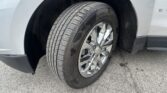 Close-up of a vehicle tire and chrome wheel in the wheel well of a silver SUV pickup or van variant.