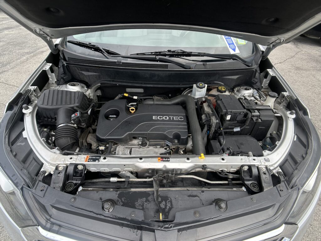 Front view of an engine bay with Ecotec cover and exposed components under the hood of a car.