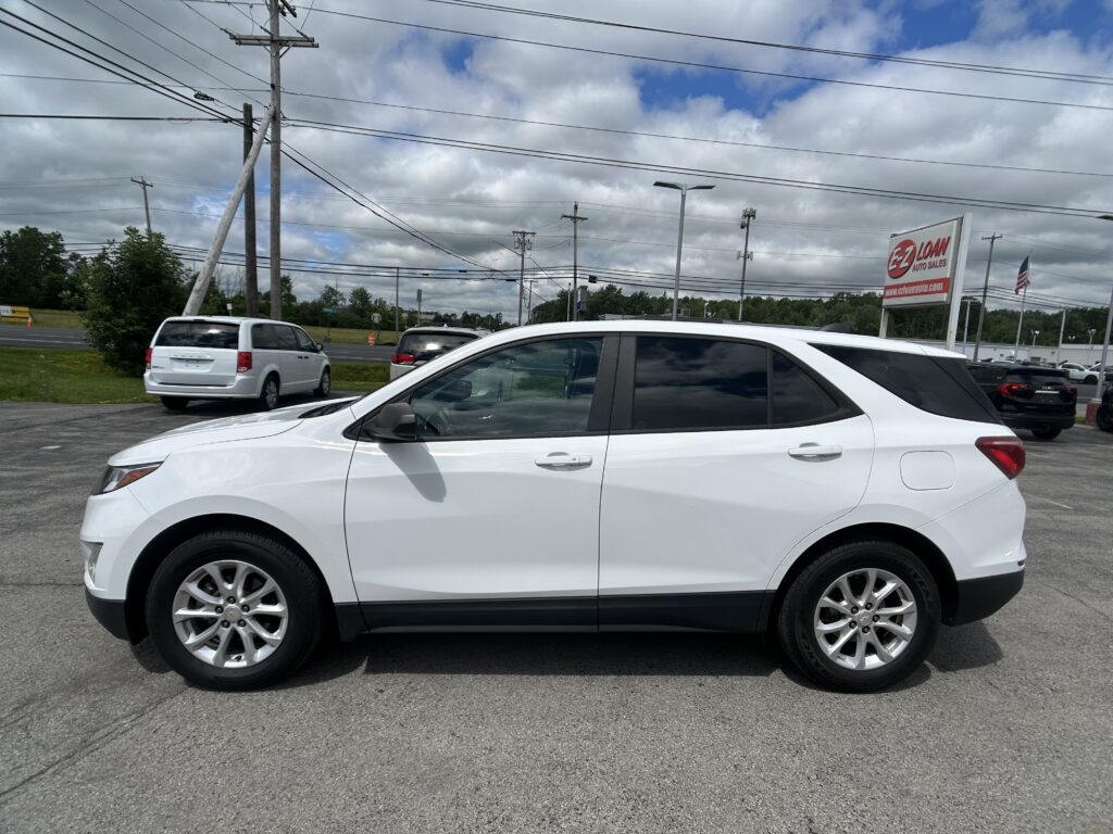 White SUV in a car lot with overhead power lines and a red-and-white EZ Loan Auto Sales sign in the distance.