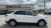 White SUV parked in front of an E-Z Loan Auto Sales dealership with other cars and a showroom in the background under a cloudy sky.