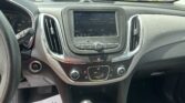 Driver's view of the car interior: center touchscreen radio on FM, climate controls below, gear shifter in the foreground.