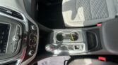 Interior of a car showing the center console, gear shifter, cup holder with keys, and a gray patterned passenger seat.