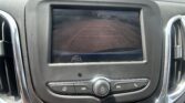 Rearview camera display showing orange parking guidelines on a parking lot surface behind the car.