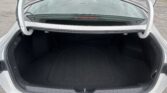 Open car trunk with black interior and visible rear window; empty cargo space in a white sedan