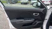 Open front passenger door view showing black interior panel and window controls, with a car dealership lot of white and gray SUVs visible outside a white SUV.