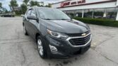 Gray Chevrolet SUV in a parking lot past an E-Z Loan Auto Sales storefront with a cloudy sky in the background