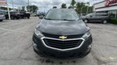Front of a gray Chevrolet SUV in a parking lot near an EZ Loans dealership with other cars and cloudy sky in background