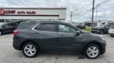 Side view of a dark gray Chevrolet Equinox parked in a dealership lot, with the EZ LOAN AUTO SALES building in the background.