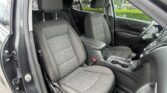 Front interior of a car with driver and passenger seats, center console with two cup holders, and steering wheel visible through the open door