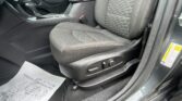 Driver's-side car interior focusing on the seat and center console, with gear shifter and seatbelt buckle visible, and a paper on the floor mat