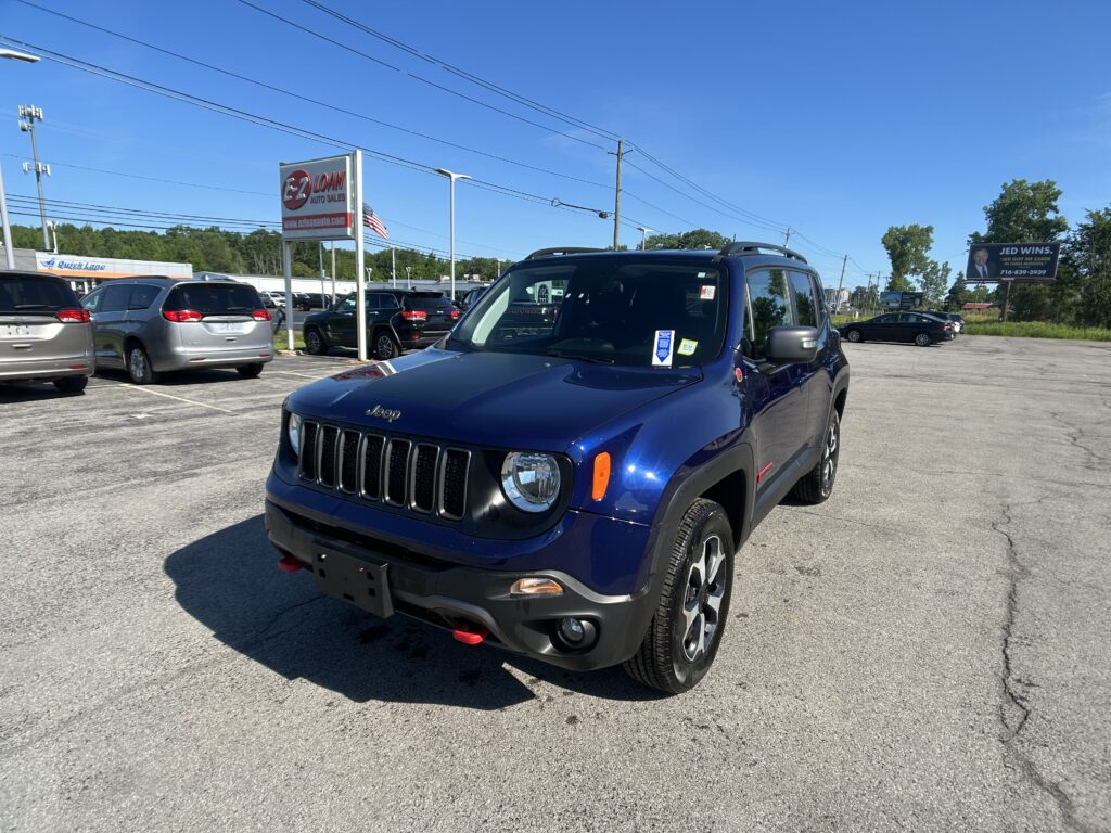 Blue Jeep SUV in a dealership parking lot with an EZ Loan Auto Sales sign in the background and other cars nearby.