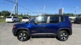 Blue SUV parked in a car dealership lot with other vehicles, power lines, and a clear blue sky in the background.
