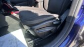 Front passenger area of a blue car: black seats with red stitching, gear shifter, center console, and a document on the floor mat.