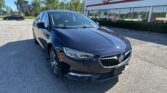 Front-left view of a dark blue Buick sedan parked in a car lot outside EZ Loan Auto Sales.
