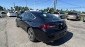 Black sedan in the foreground of a busy parking lot on a sunny day with a clear blue sky and power lines overhead.