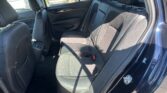 Back seat area of a car with black fabric upholstery, three headrests, and visible seat belts in the rear row.