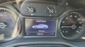 Dashboard view with center touchscreen showing 'Hood Open' warning and a blue car illustration, flanked by speedometer and tachometer gauges.