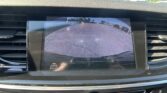 Rearview camera display showing a parking lot with orange guide lines to assist backing up