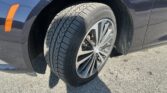 Close-up of a car wheel and tire on a dark blue vehicle, showing alloy rim and tread pattern.