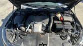 Front of a car with the hood open, exposing the engine bay and battery on the right side.
