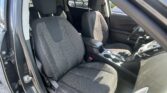 Right-hand-drive car interior with black fabric seats and red stitching; front seats, center console, and steering wheel visible.