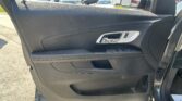 Interior car door panel with silver door handle and window controls; view of parked cars through the window side mirror in a bright lot
