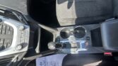 Interior of a car front passenger area showing the center console with cup holders, gear shift, and climate controls visible near the driver seat edge.