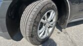 Close-up of a tire and silver alloy wheel in the front wheel well of a dark SUV.