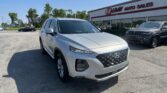 Front corner of a white Hyundai SUV in a dealership lot with EZ LOAN AUTO SALES building in background.