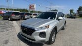 Front-angle shot of a silver SUV in a dealership lot with an EZ Loan Auto Sales sign and clear blue sky in the background (power lines visible).