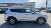 White SUV parked in front of the E-Z Loan Auto Sales dealership on a sunny day with a blue sky.