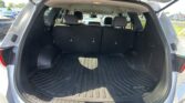 Open hatchback showing cargo area with black mat and upright third-row seats in a SUV