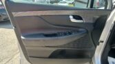 Car interior door panel featuring window controls and a silver door handle, with a parking lot visible through the window behind.